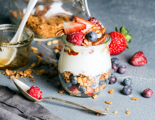 Yogurt oat granola with fresh berries, nuts, honey and mint leaves - Stock Photo - Images