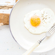 Fried egg with spice and bread slices in white ceramic frying pan on wooden  board Stock Photo by sonyakamoz