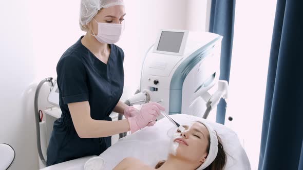 Cosmetologist Smears Girl's Face with Cream in Beauty Salon alt