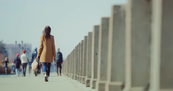 Young Elegant Woman Walks Along a Crowded Street alt