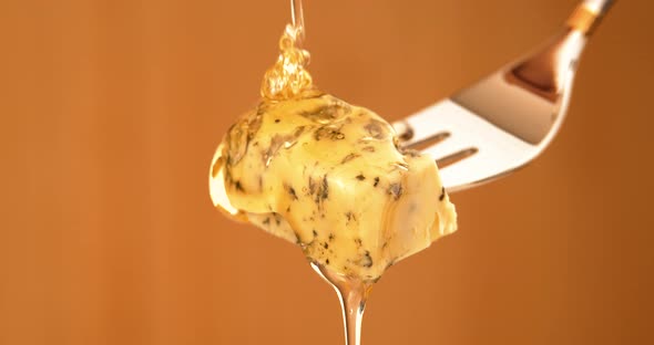 Liquid Organic Honey Dripping on a Fork with Dorbly Cheese on a Light Background alt