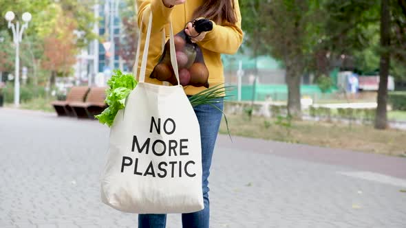 A Woman Puts Vegetables and Fruits in a Fruit Bag with the Inscription No More Plastic alt