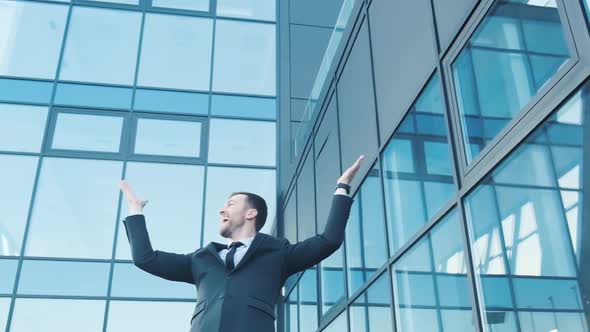 A Young Smiling Office Worker He Spread His Arms Wide Looks Around and Rejoices alt