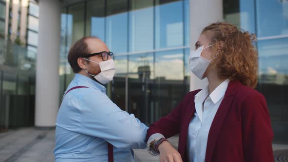 Colleagues in Medical Mask Greeting Touching Elbows Meeting Outdoors alt