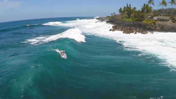 Aerial view of a man sup stand-up paddleboard surfing in Hawaii. alt