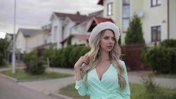 Portrait of Beautiful Woman in Long Mint Dress Keeps the Hat Away From the Wind