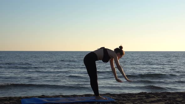 Young Caucasian Woman Practicing Yoga on the Beach Near Calm Sea, Sunrise Background.