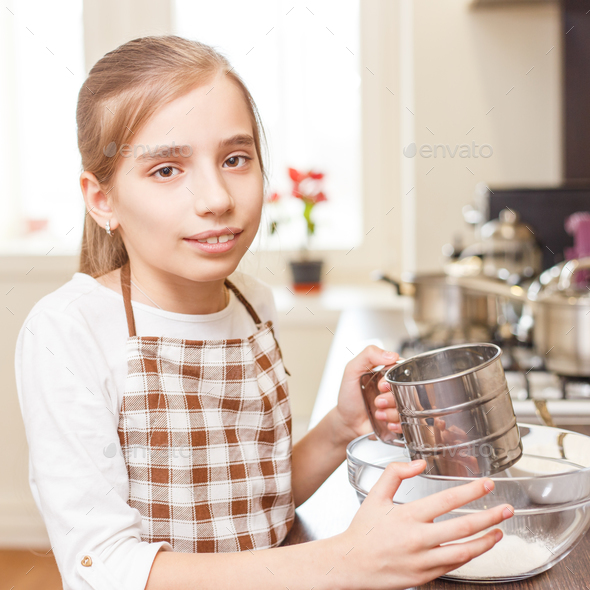 Young teenage girl sieving flour through the sieve