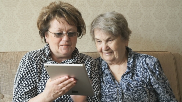 Two Elderly Women Watch Pictures Using a Tablet