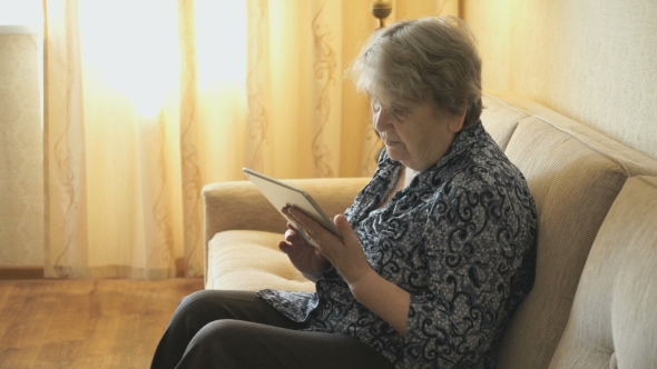 Old Woman Looks At Pictures Using a Digital Tablet