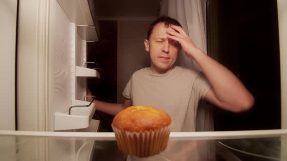 Refrigerator of a lonely young man, one spoiled cupcake on the shelf alt