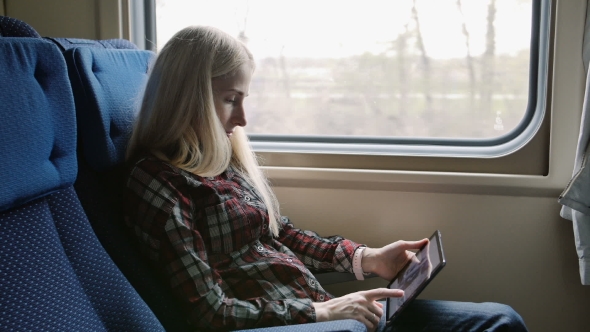 Young Woman Using Tablet While Traveling By Train
