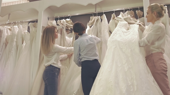 Smiling Pretty Group Of Brides Chooses White Dress At Shop Of Wedding Fashion alt