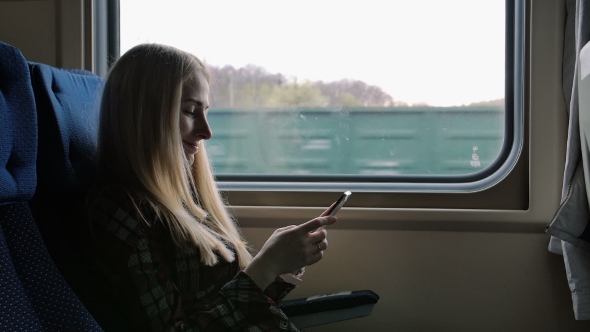 Young Woman Using Smartphone While Traveling By Train alt