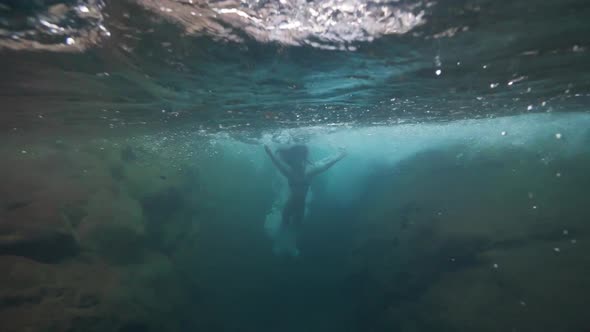 A Brave Female Tourist Jumps Into the Swift Stream in a Waterfall at Summer alt