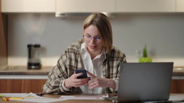A Happy Smiling Woman Holds a Mobile Phone in Her Hands and Laughs Looking at the Screen alt
