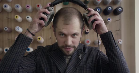 Man Putting on Headphones Nodding Head with Closed Eyes Then Looking at Camera alt