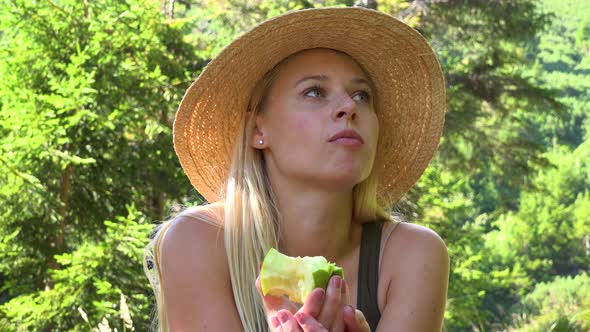 A Young Beautiful Woman Sits in a Forest on a Sunny Day and Eats an Apple - Closeup alt