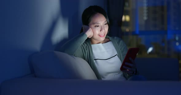 Asian woman look at cellphone and sit on couch alt