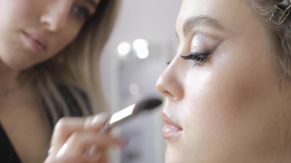 Makeup Artist Is Applying Blush Bronzer Using Brush To Young Model Cheek