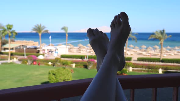 Woman Feet Relaxing On Balcony Of Hotel With Idyllic Sea View alt