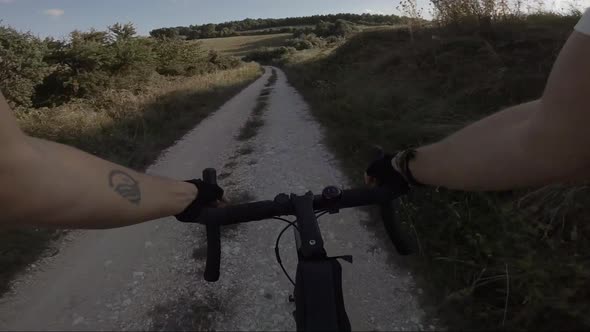 Biker riding downhill on dust road, Marche, Italy alt