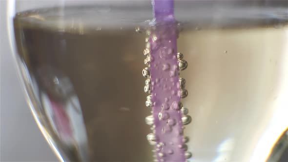A purple tube in a cocktail glass. Bubbles with gas rise up close-up. macro photography.