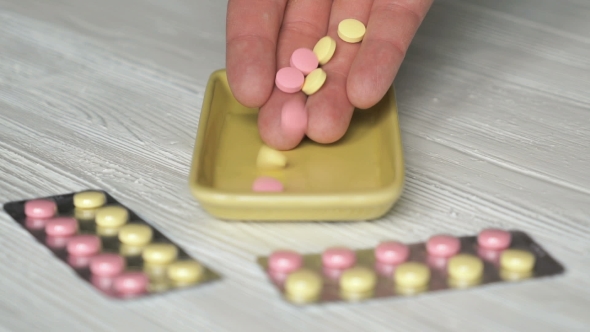 Hand Folds Pills In Container Placed On The Table