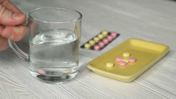 Man's Hand Takes The Pills From a Yellow Container alt
