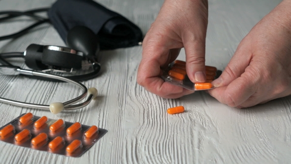 Hand Pulls Out The Pills From a Blister Card alt