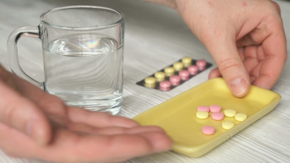 Man's Hand Takes The Tablets From The Container alt