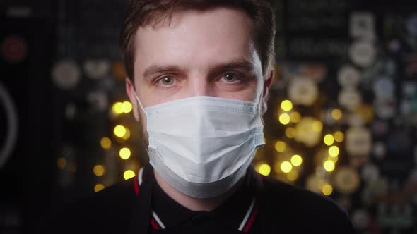 Portrait of waiter in apron and medical mask. Close up face in mask. Reopen small business. alt