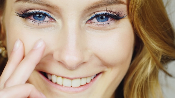 Portrait Of a Young Blue-eyed Woman Stroking Her Face With His Fingertips alt