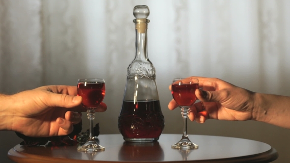 Two Hands Clink Glasses With a Liquor Of Red Color