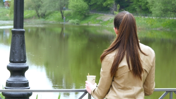 Back View Of Young Girl Drinking Cup Of Takeaway Coffee From Disposable Cup. 