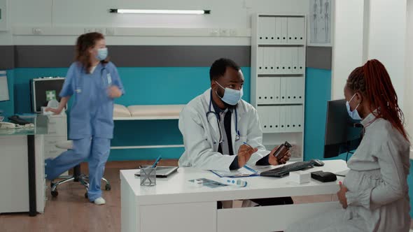 Medic and Pregnant Woman with Face Mask Talking About Pills Treatment alt