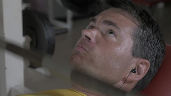 Young Man Working Out Hard With Bench Pressing alt