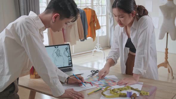Two Fashion Designers Working With Laptop And Sketching At Fashion Design Studio alt