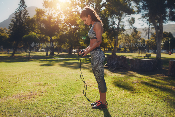 Fit young woman with skipping rope outdoors at the park