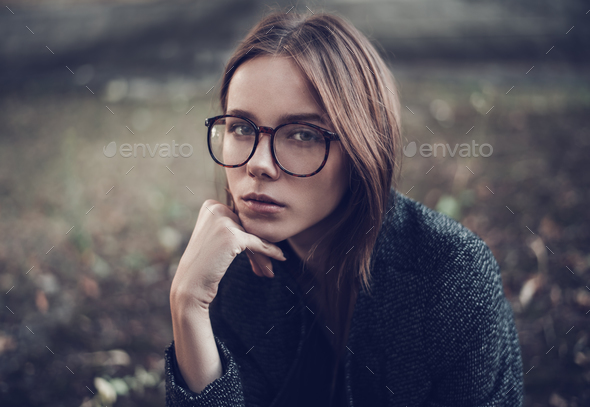 Pensive sad beautiful young woman in stylish sunglasses closeup on a city street