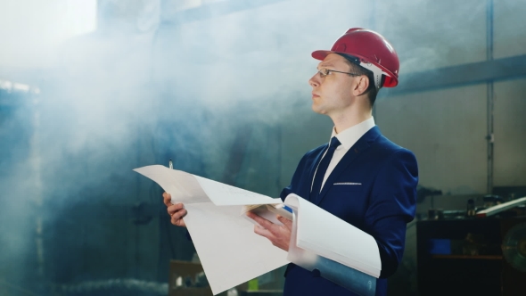 The Engineer In a Suit And a Helmet Studies Blueprints Indoors alt