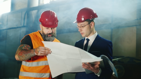 Architect And Builder Studying Together Blueprints At a Construction Site alt