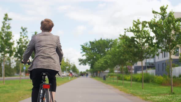 Young Man Riding Bicycle on City Street alt