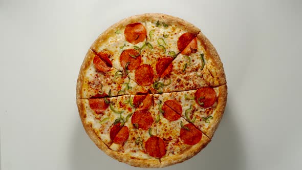 Whole Circle Of Big Pizza Is Rotating On A White Surface