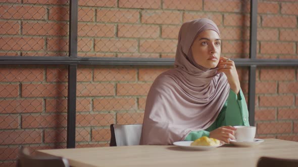 Muslim Woman Having Coffee in Cafe alt