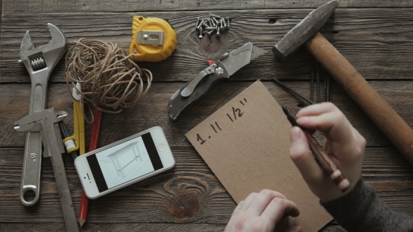 Man at Desk Calculating.  Props Include Blank Sheet of Craft Paper, Calipers and Hummer alt