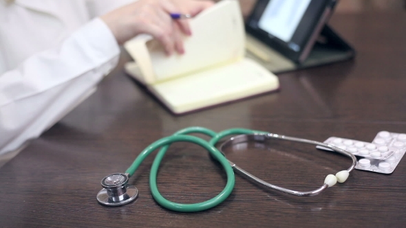 Doctor Working With Tablet Computer And Documents