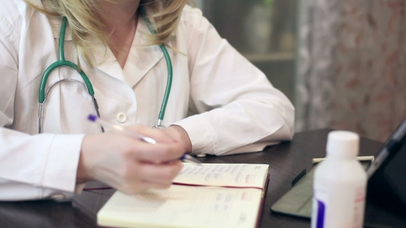 Doctor Working With Tablet Computer And Documents