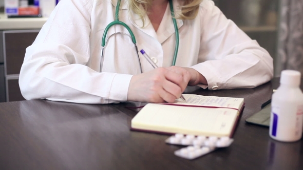 Doctor Working With Tablet Computer And Documents