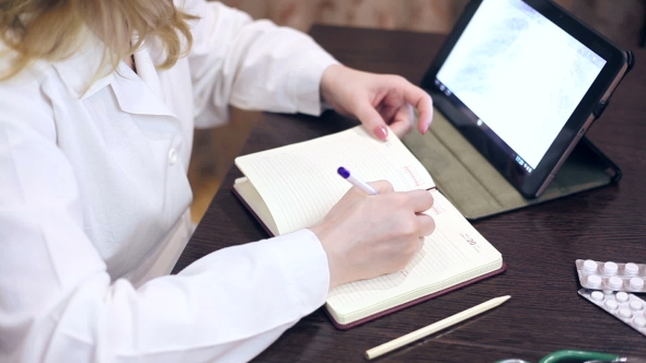 Doctor Working With Tablet Computer And Documents